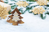 Christmas frame with gift, the branches of the Christmas tree and wooden decorations on snow background. Simple Christmas composition with free space