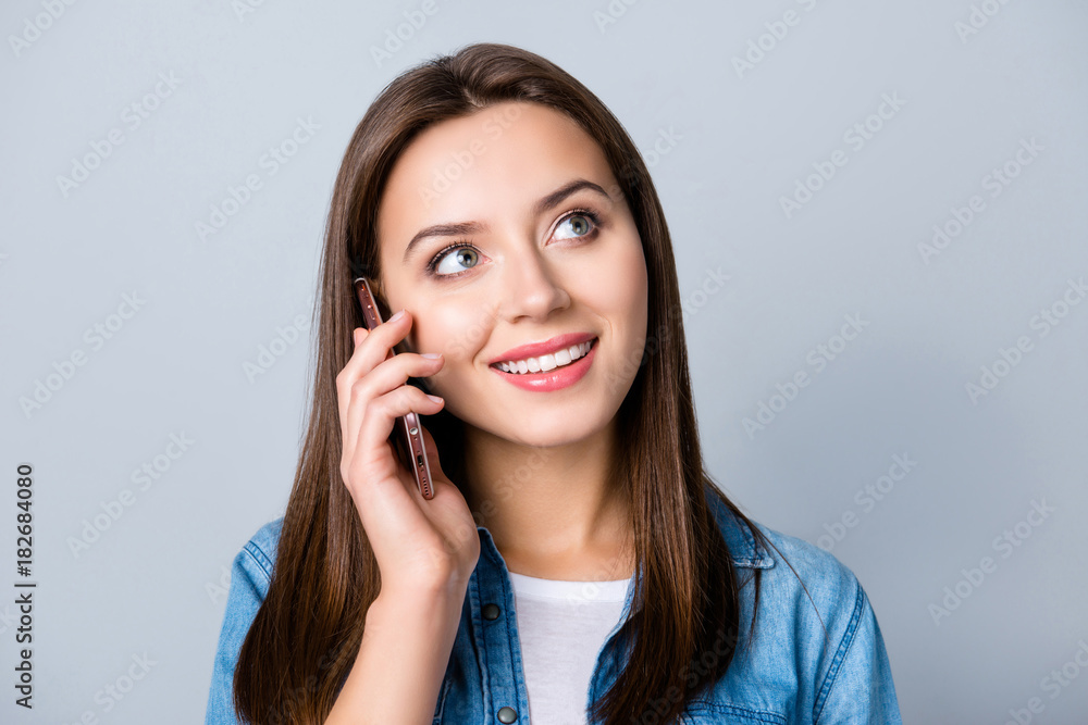 Close up portrait of young, brunette girl speaking on smart phone with her lover, standing over grey background Close up portrait of young, brunette girl speaking on smart phone with her lover, standing over grey background