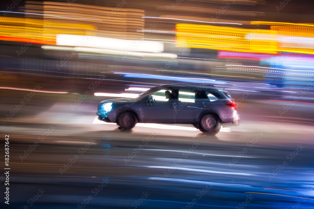 Automobile che sfreccia veloce di notte per le vie con luci colorate di una  grande città 