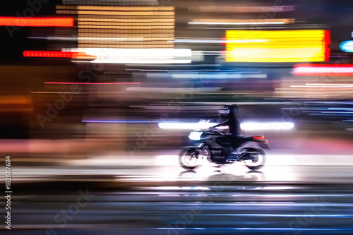 Motocicletta che sfreccia veloce di notte per le vie con luci colorate di una  grande città metropolitana  photo