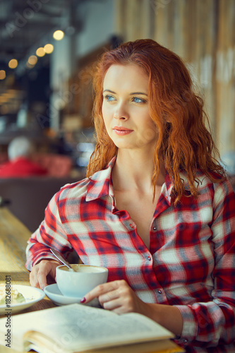 Konstfotografi Red haired woman reading book  in cafe. City break  concept