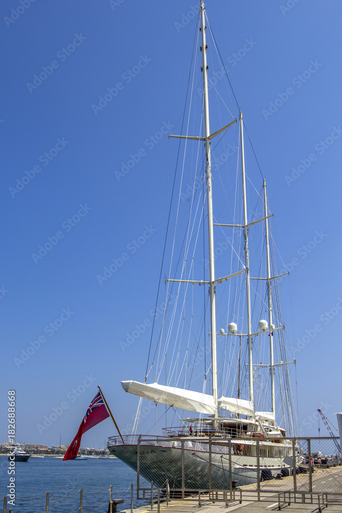 A large sailing ship stands in the port on the dock with the sails lowered. A large sailing ship stands in the port on the dock with the sails lowered.