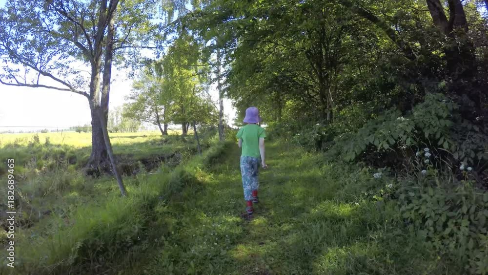 Little girl walking on green footpath. Summer lifestyle moment of a happy childhood. Little girl walking on green footpath. Summer lifestyle moment of a happy childhood.