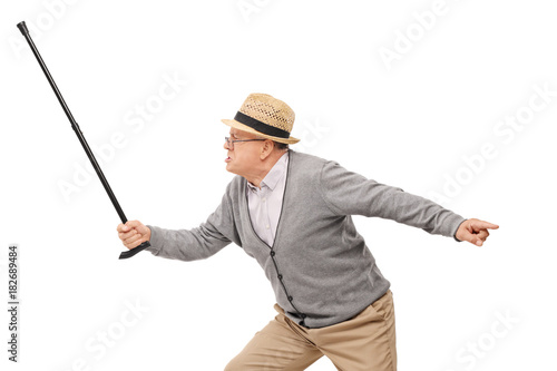 Angry elderly man holding a cane as a sword