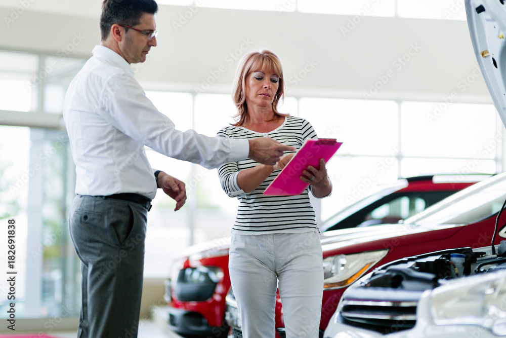 Obraz premium Professional salesperson selling cars at dealership to buyer