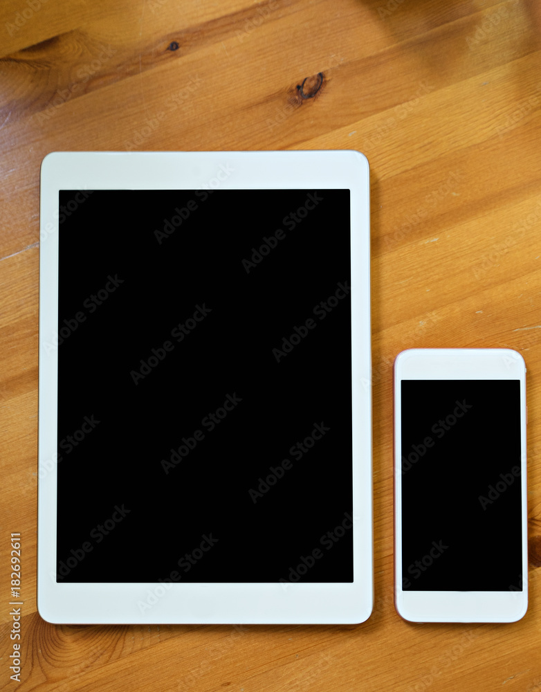 smart phone and tablet in white color. Black screen for mock up put on wood background smart phone and tablet in white color. Black screen for mock up put on wood background