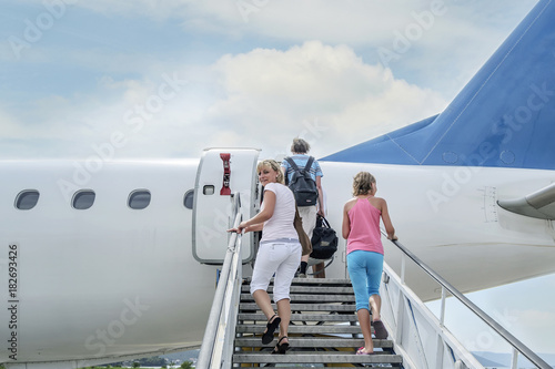 Joyful people climb the ladder into the plane ready for departure