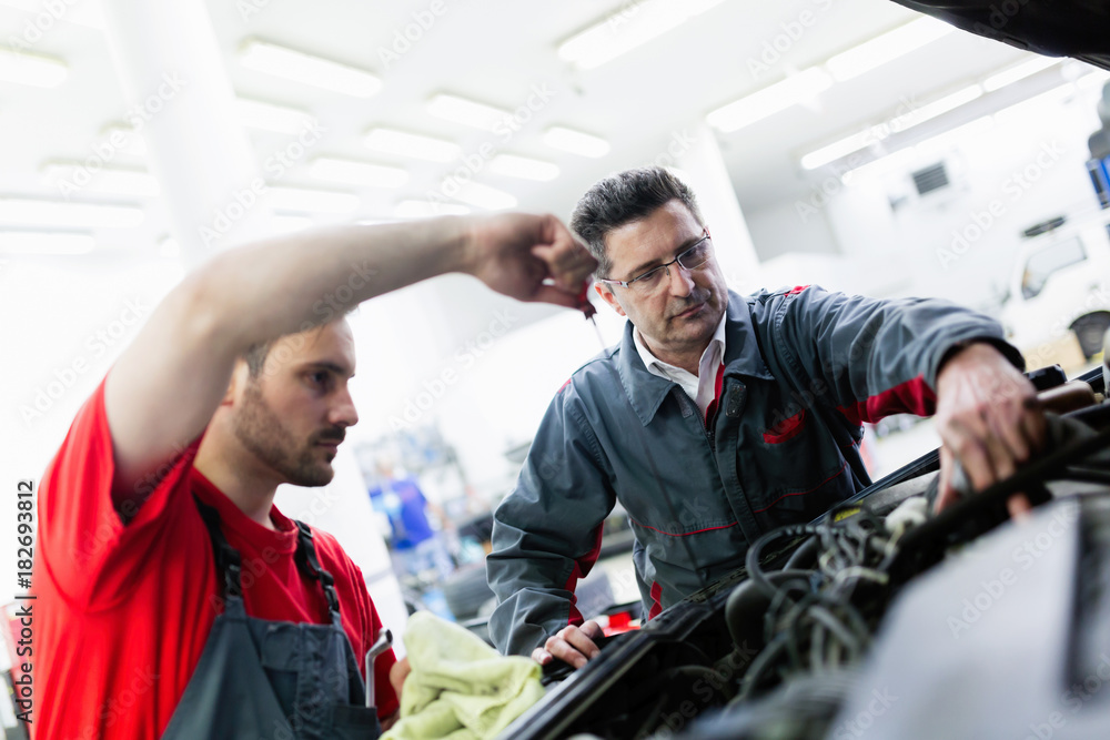 Car mechanics working at automotive service center Car mechanics working at automotive service center