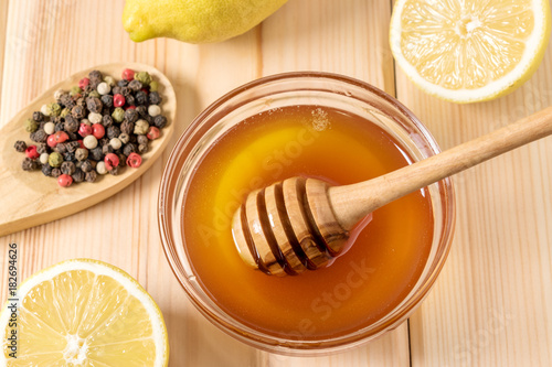 Honey with lemon and spice on a wooden background.