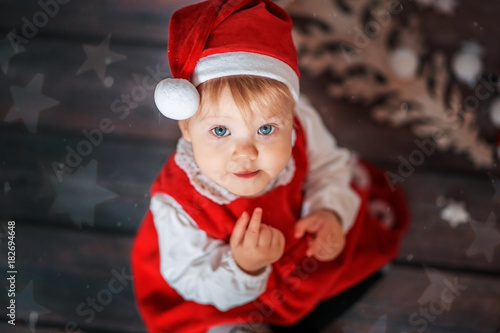 Little girl in Santa hat on Christmas background.