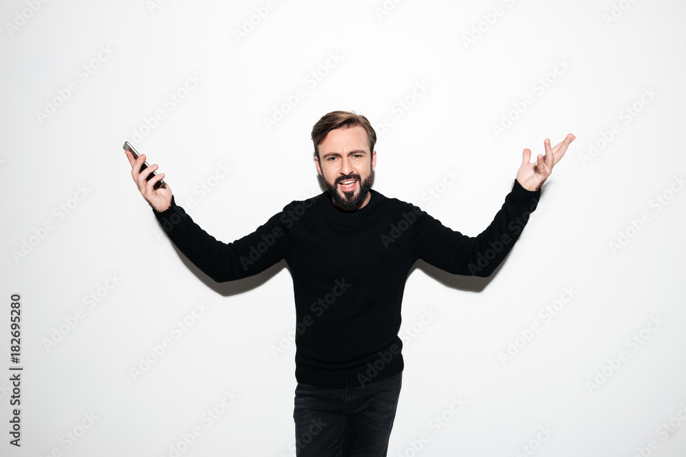 Portrait of a confused puxxled man holding mobile phone