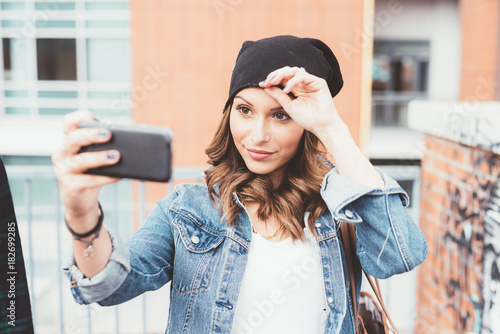 young woman outdoors using smart phone taking selfie - technology, vanity, sharing concept