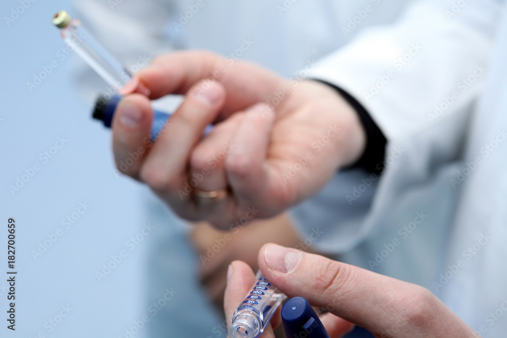 Insulin cartridge and ampoule in the hands of a doctor. The doct Insulin cartridge and ampoule in the hands of a doctor. The doct