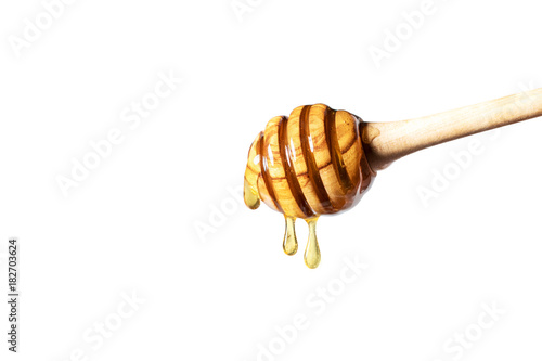 Honey dripping from honey dipper on white background. Thick honey dipping from the wooden honey spoon. Healthy food concept.