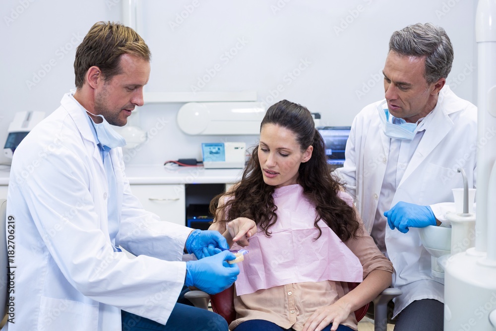 Dentist showing model teeth to patient Dentist showing model teeth to patient