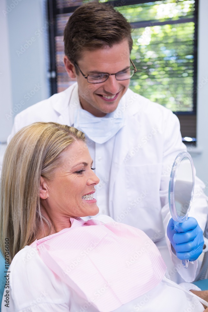Fototapeta premium Dentist showing mirror to smiling patient