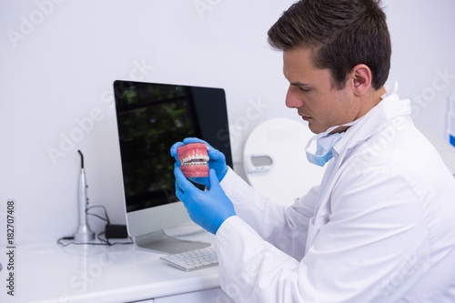 Dentist holding dental mold while sitting by computer photo