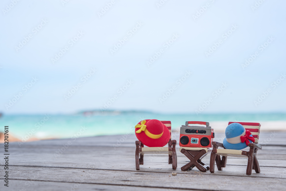 Naklejka premium Miniature radio on a table and beach chair with sea background.