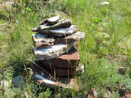 Folded flat stones on a rock on background grass