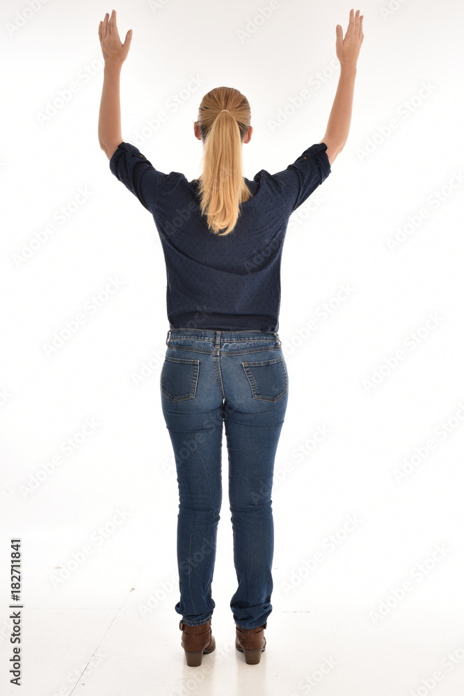 Full length portrait of a girl wearing simple blue shirt and jeans, standing pose facing away on a white background. Full length portrait of a girl wearing simple blue shirt and jeans, standing pose facing away on a white background.