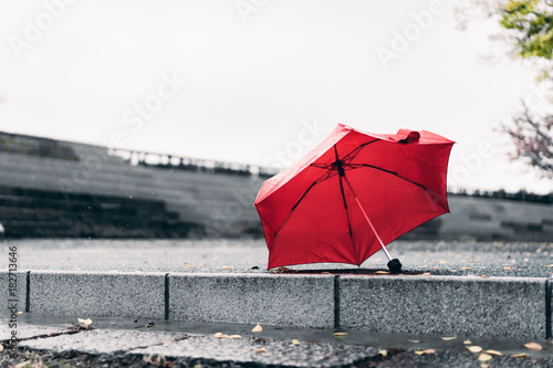 Red umbrella on concrete floor with raining in the park., vintage image., lonely concept., copy space for text.