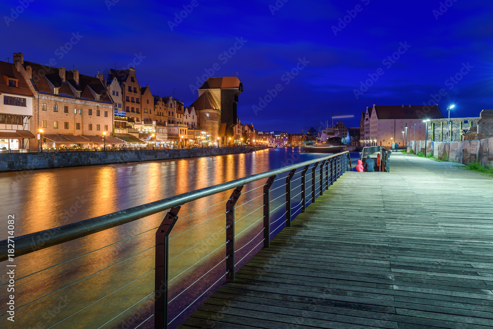 Promenade in Old town of Gdansk with famous historic port crane reflected in Motlawa river. Poland, Europe.