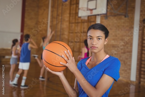 High school girl holding a basketball while team playing in