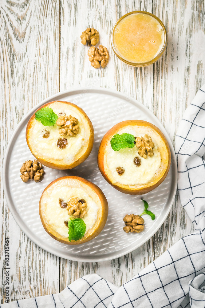 Cheesecake stuffed baked apples on white rustic wooden background. Top view, space for text.