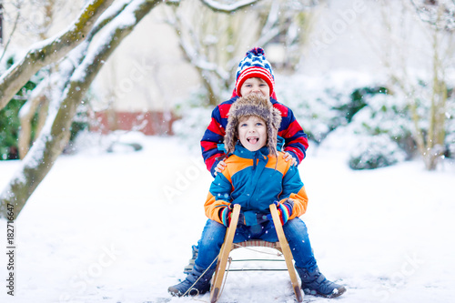 Two little kid boys enjoying sleigh ride in winter