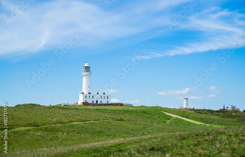 Flamborough, Yorkshire, UK. View of the modern lighthouse on top of the chalk cliffs at Flamborough Head. To the right is the disused old lighthouse and coastguard station.