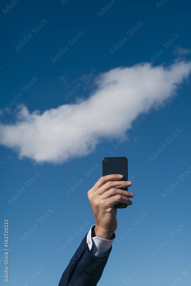 Hand holding smartphone on blue sky background Hand holding smartphone on blue sky background