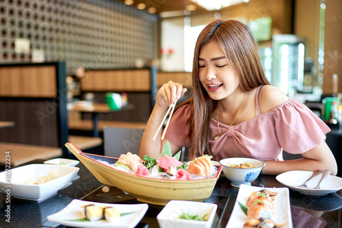 Beautiful asian woman eating sashimi, Japanese food.