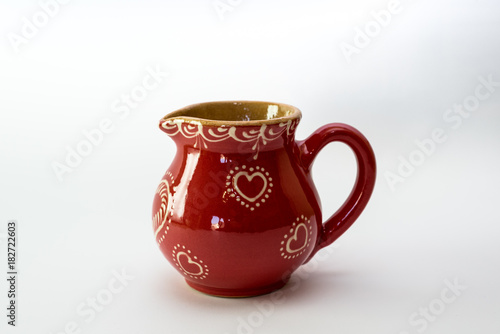 Decorative red jug, in vintage design. Isolated on a white background