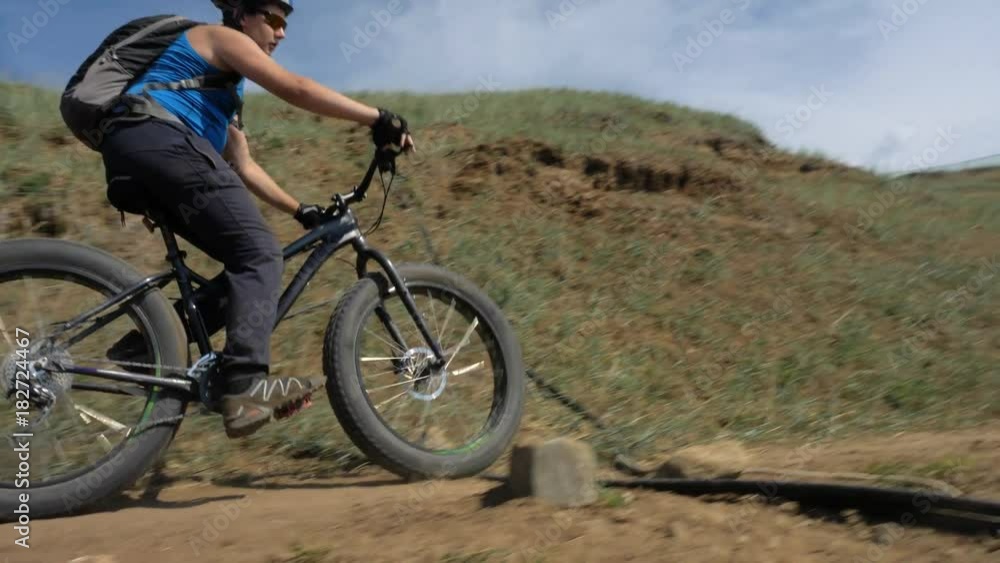 Fat bike also called fatbike or fat-tire bike in summer driving on the road. The guy is riding along the sand clay path by the hill. Applies severe braking. Fat bike also called fatbike or fat-tire bike in summer driving on the road. The guy is riding along the sand clay path by the hill. Applies severe braking.