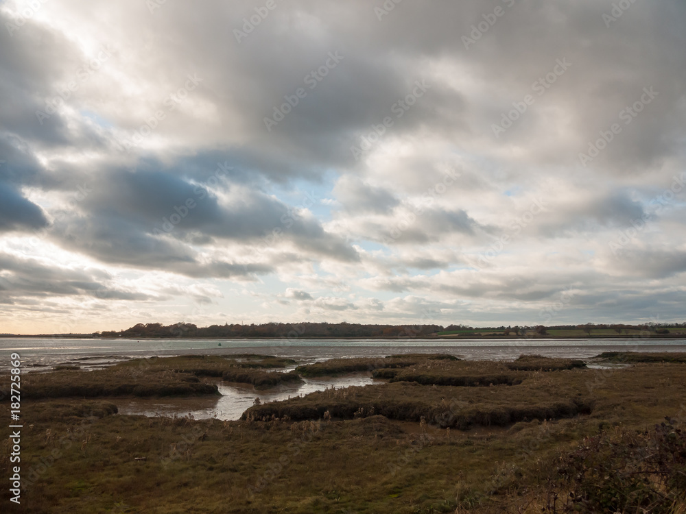 stunning dramatic cloud sky over estuary lake river ocean coastline landscape