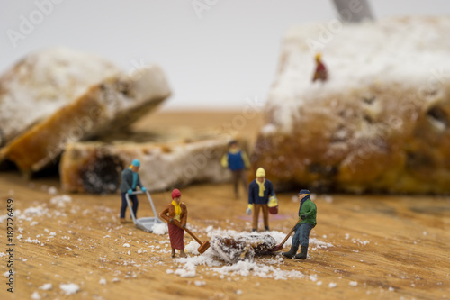 Miniature people shoveling snow from board