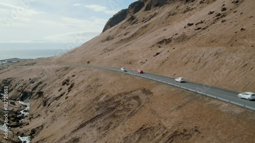 Car driving along Icelandic mountain road crossing other white and red car