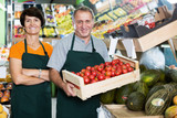 Smiling couple employees is standing with box with tomatos