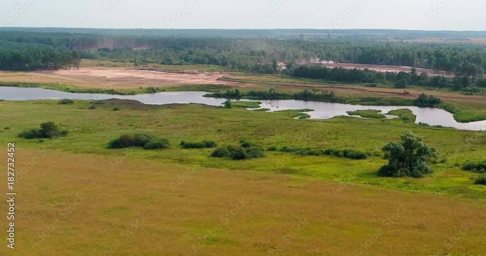 Bend of river aerial view from flying quadcopter over forest. Landscape panorama. Beautiful nature. Horizon in the background of fields of meadows and sky.