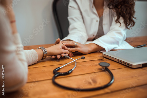 Hand of doctor reassuring her female patient.