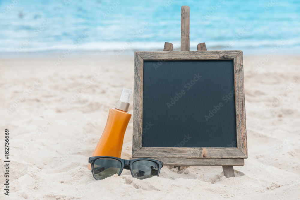 Chalk board with sunscreen cream in the sand on the beach tropic exotic background Chalk board with sunscreen cream in the sand on the beach tropic exotic background