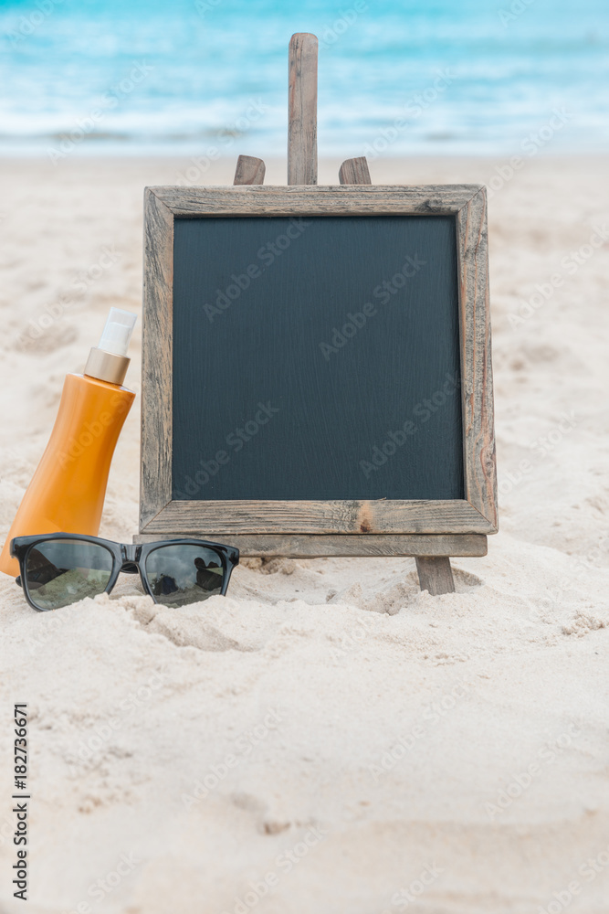 Chalk board with sunscreen cream in the sand on the beach tropic exotic background Chalk board with sunscreen cream in the sand on the beach tropic exotic background