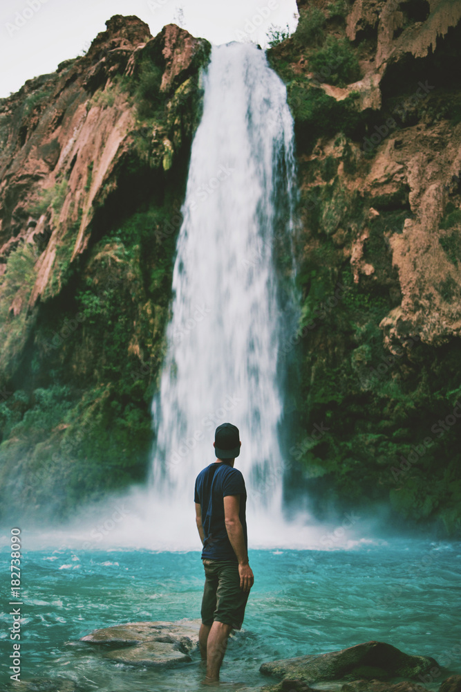 Fototapeta premium Man in front of beautiful blue waterfall