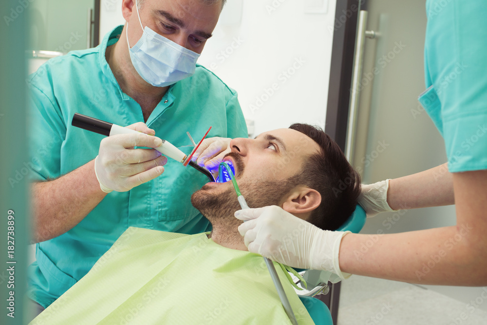 Dentists examining and working on male patient.Dentist's office. Dentists examining and working on male patient.Dentist's office.