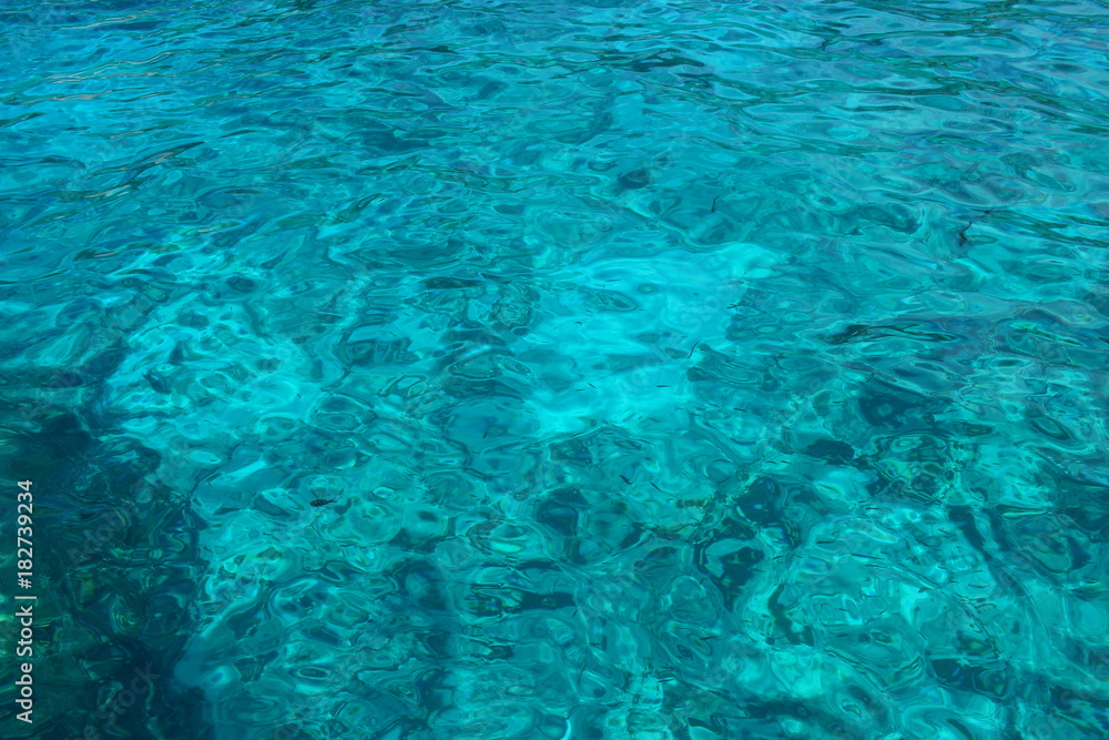 Background of a transparent bright tropical sea of turquoise color on a sunny summer day.