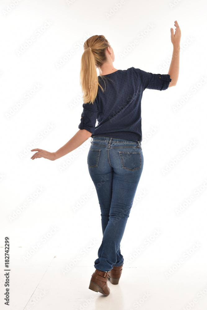 Full length portrait of a girl wearing simple blue shirt and jeans, standing pose facing away on a white background. Full length portrait of a girl wearing simple blue shirt and jeans, standing pose facing away on a white background.