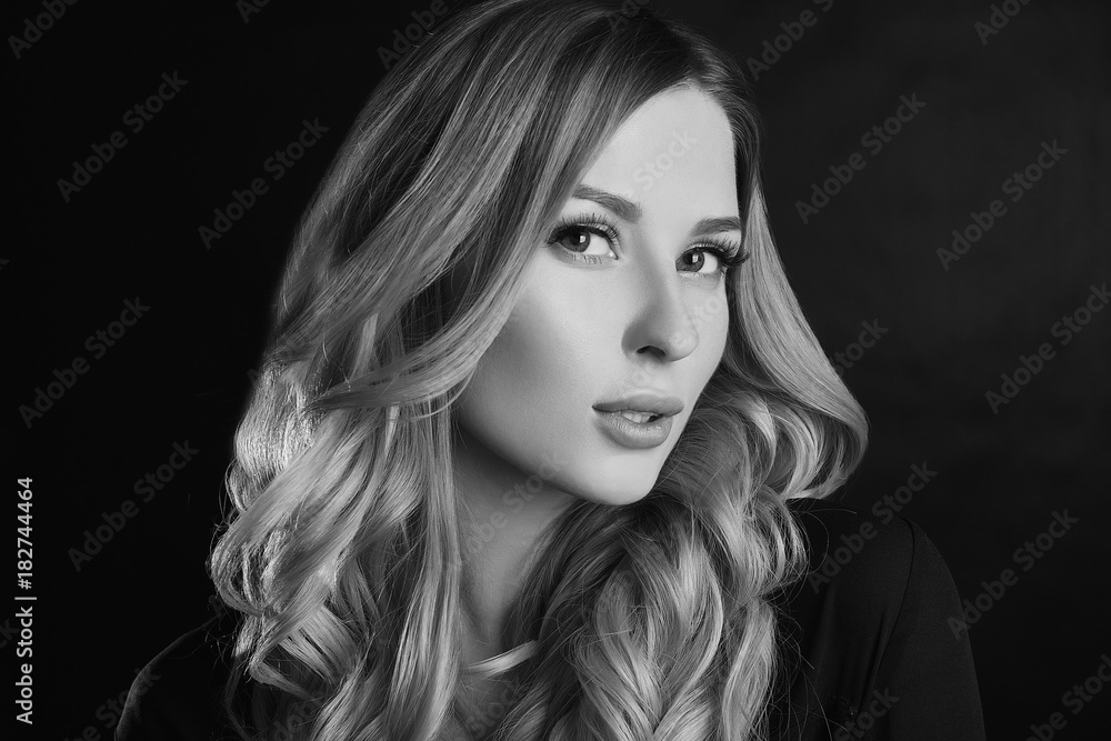 Beautiful blonde woman with curly hair posing on black background