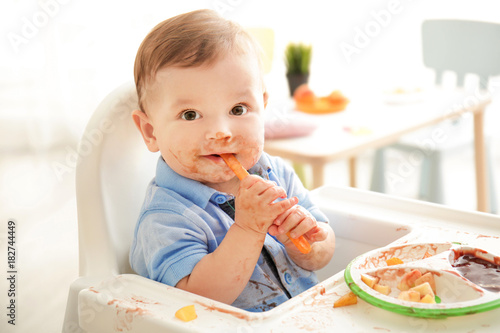 Cute messy baby eating pure...