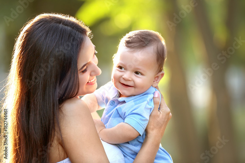 Beautiful young mother holding cute baby boy, outdoors