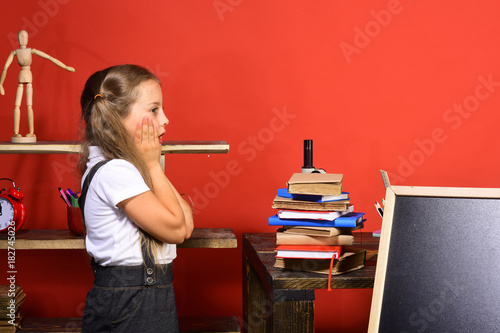 Kid and school supplies on red wall background